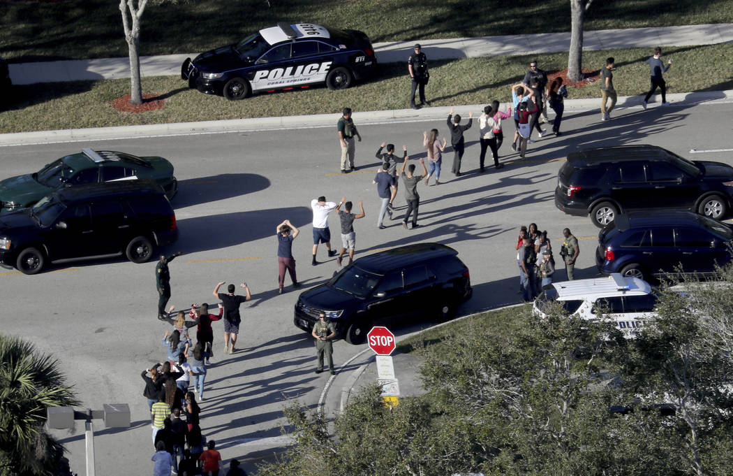 Students hold their hands in the air as they are evacuated by police from Marjorie Stoneman Douglas High School in Parkland, Fla., after a shooter opened fire on the campus. (Mike Stocker/South Fl ...