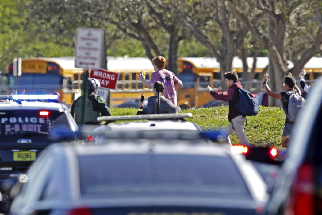 Students run with their hands in the air following a shooting at Marjory Stoneman Douglas High School in Parkland, Fla., Wednesday, Feb. 14, 2018. (John McCall/South Florida Sun-Sentinel via AP)