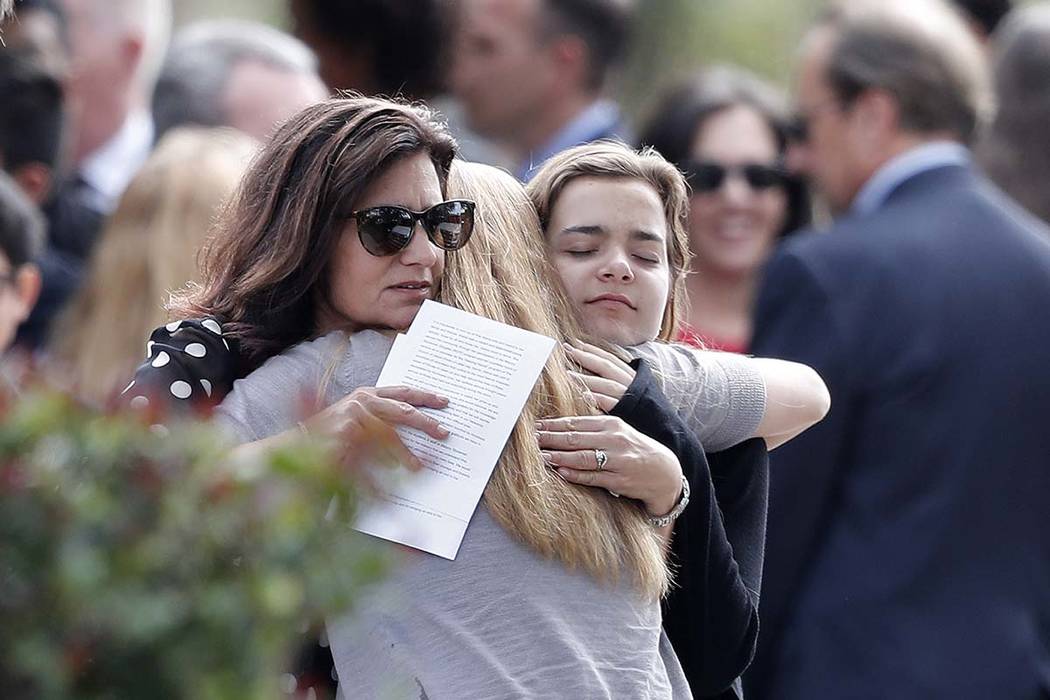 Mourners hug as they leave the funeral of Alaina Petty, in Coral Springs, Florida, Monday, Feb. 19, 2018. Petty was a victim of Wednesday's mass shooting at Marjory Stoneman Douglas High School. ...