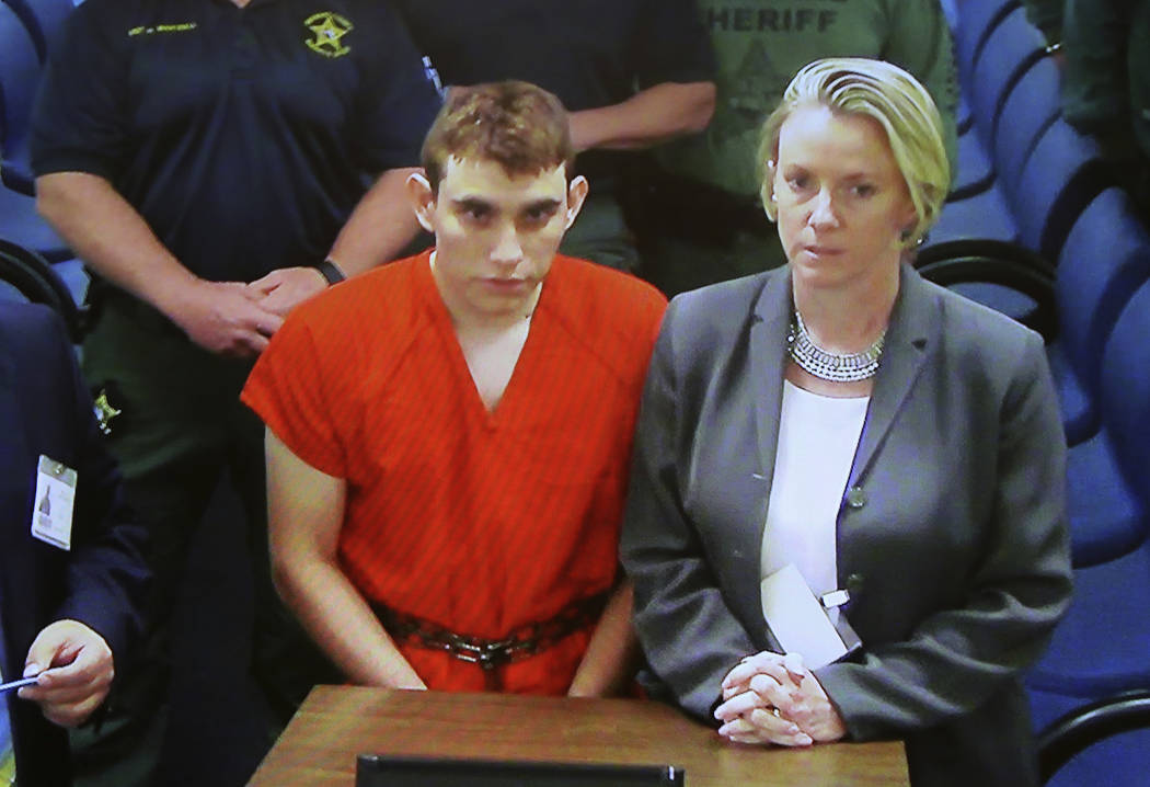 A video monitor shows school shooting suspect Nikolas Cruz, left, making an appearance before Judge Kim Theresa Mollica in Broward County Court, Thursday, Feb. 15, 2018, in Fort Lauderdale, Fla.   ...