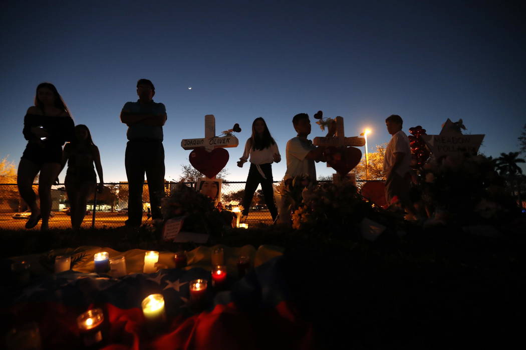 People visit a makeshift memorial outside Marjory Stoneman Douglas High School, where 17 students and faculty were killed in Wednesday's mass shooting in Parkland, Fla., Sunday, Feb. 18, 2018. Nik ...