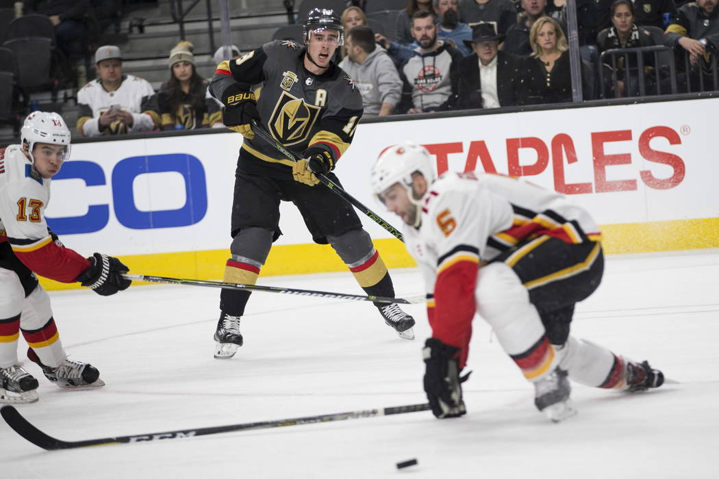 Vegas Golden Knights right wing Reilly Smith (19) makes a pass under pressure from Calgary Flames defenseman Mark Giordano (5) during the first period of an NHL game  at T-Mobile Arena in Las Vega ...