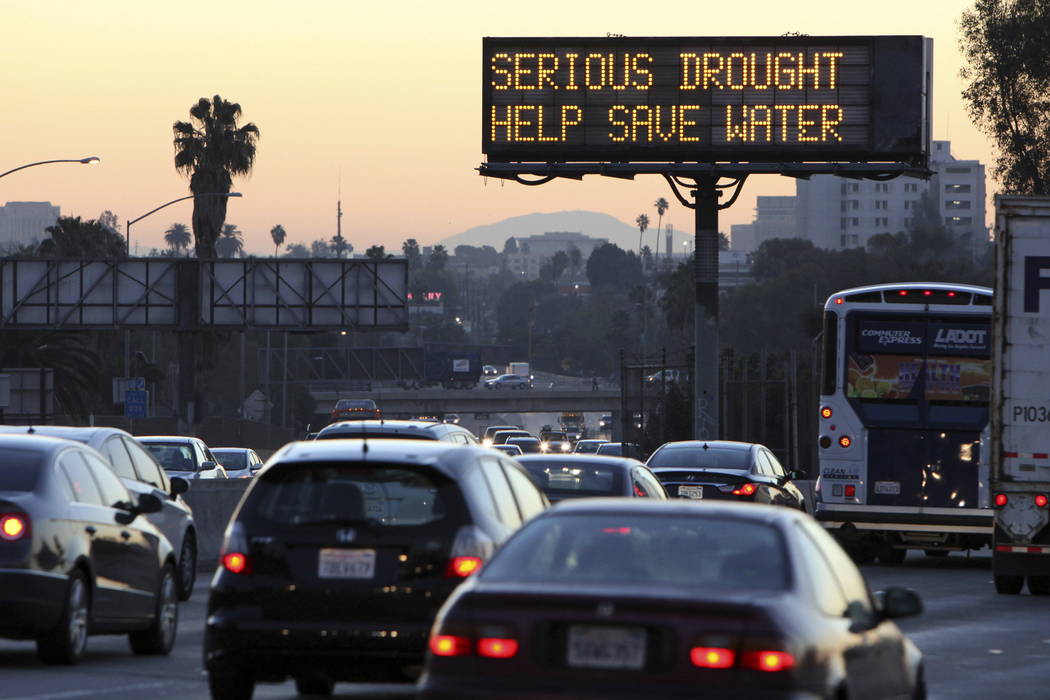 Morning traffic makes its way toward downtown Los Angeles along the Hollywood Freeway past an electronic sign warning of severe drought in 2014. (AP Photo/Richard Vogel, File)