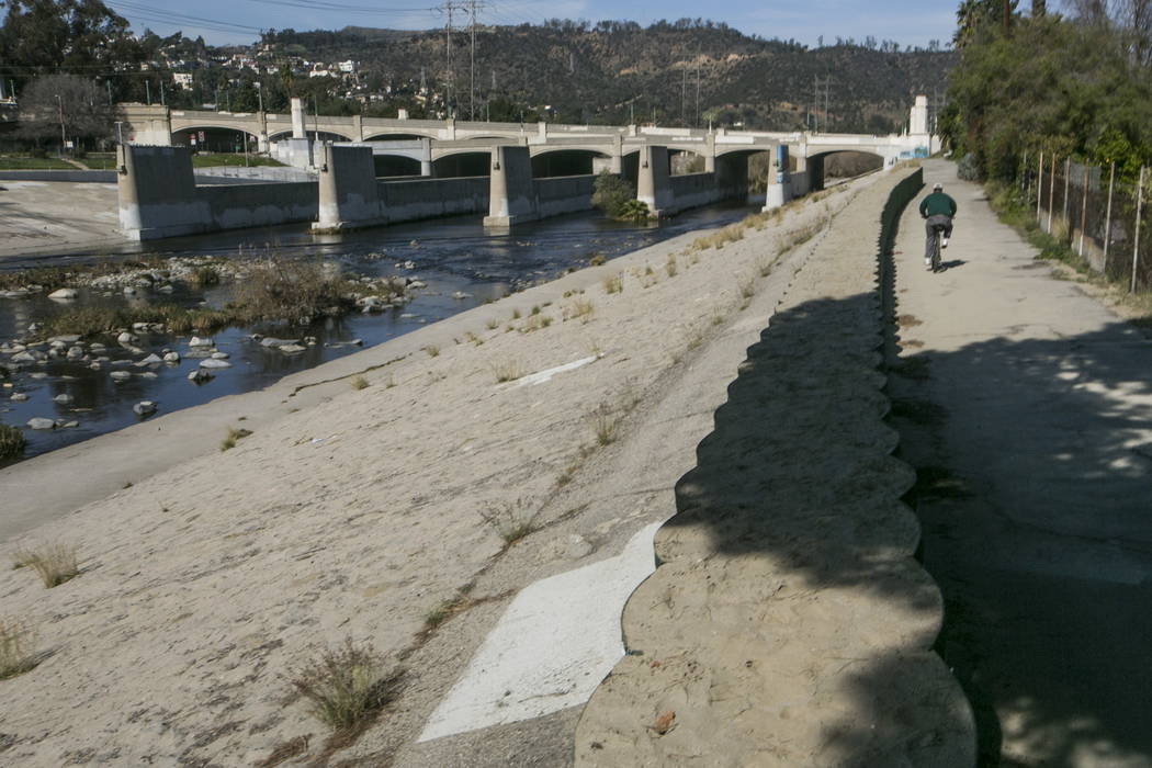 A cyclist rides along recently installed temporary flood control walls along the low level L.A. River in Los Angeles in 2016. (AP Photo/Damian Dovarganes, File)