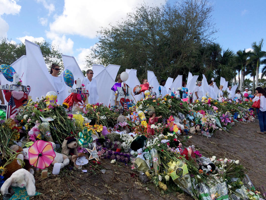 Seventeen people dressed as angels stand Sunday, Feb. 25, 2018, at the memorial outside Marjory Stoneman Douglas High School in Parkland, Fla., for those killed in a shooting on Feb. 14. Organizer ...