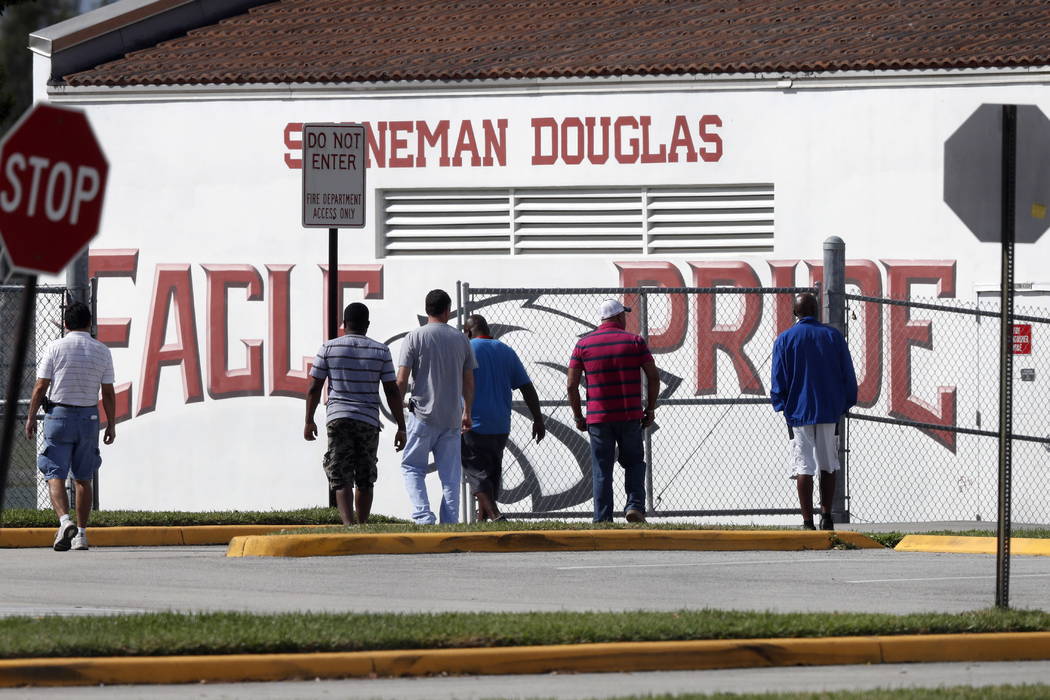 An evidence search team sweeps the grounds of Marjory Stoneman Douglas High School, in Parkland, Fla., Monday, Feb. 19, 2018, where 17 students and faculty were killed in a mass shooting. Nikolas ...
