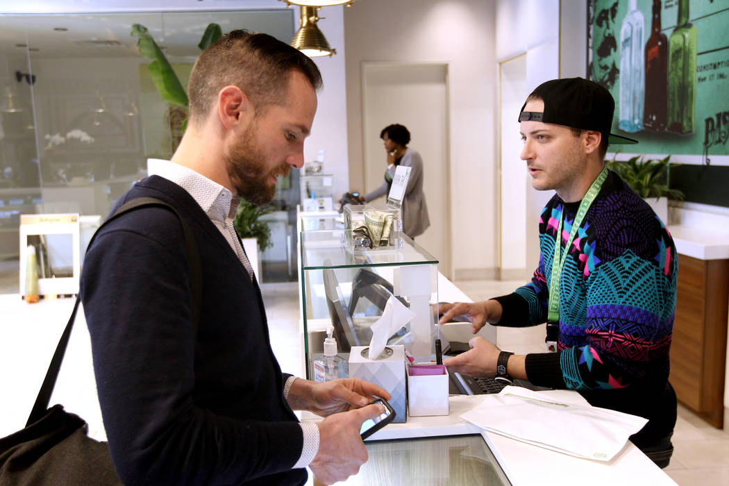 Gabriel Allred, co-founder of Tokes Platform, left, uses his cryptocurrency to make a purchase with budtender Patrick Murphy at Pisos dispensary, at 4110 S. Maryland Pkwy. in Las Vegas Monday, Jan ...