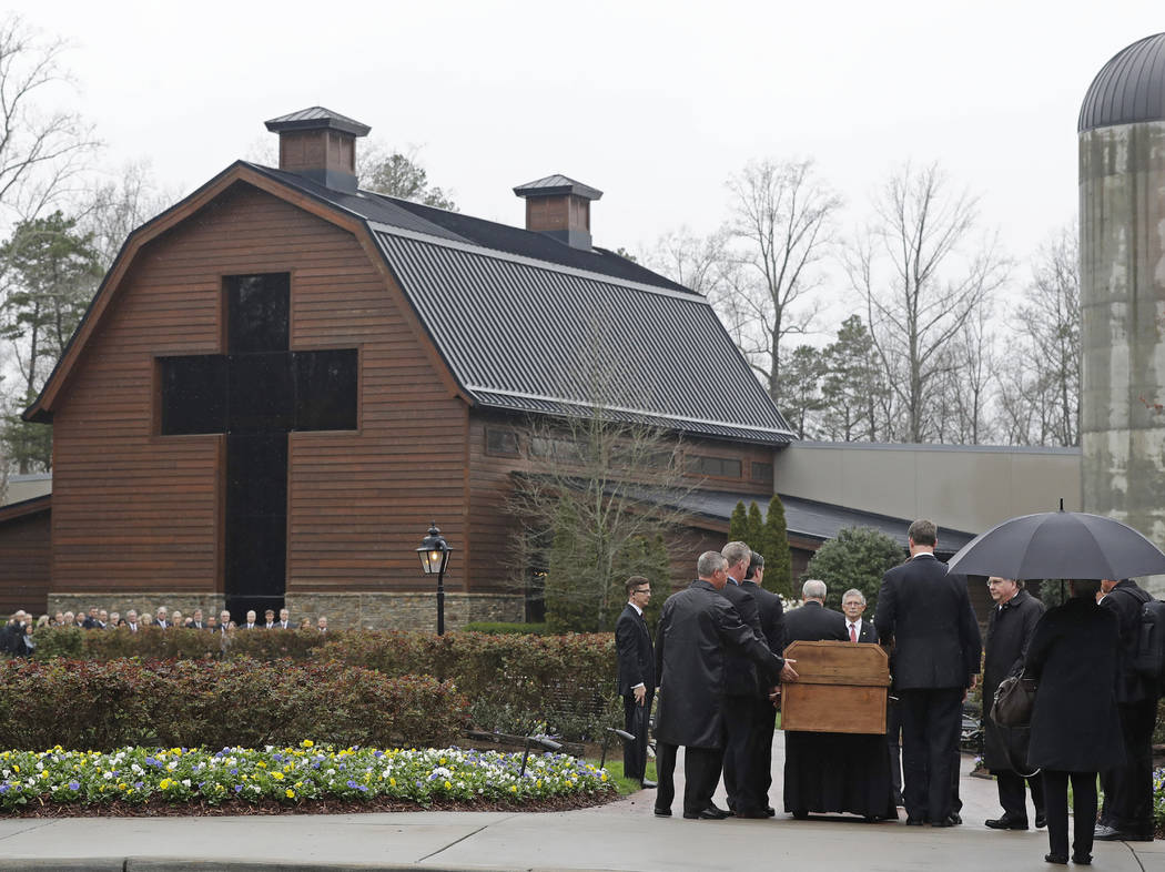 Pallbearers carry the casket of the Rev. Billy Graham past family members as it returns to the Billy Graham Library in Charlotte, N.C., Thursday, March 1, 2018. His funeral will be Friday. (AP Pho ...