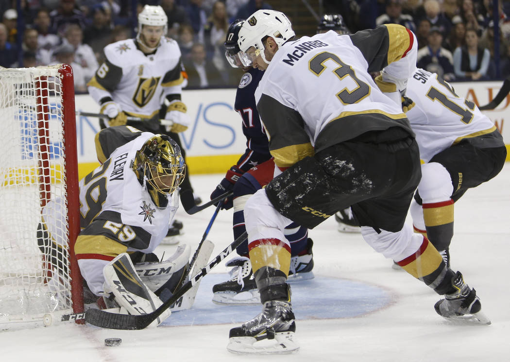 Las Vegas Golden Knights' Marc-Andre Fleury, left, makes a save as teammate Brayden McNabb, right, and Columbus Blue Jackets' Brandon Dubinsky look for a rebound during the second period of an NHL ...