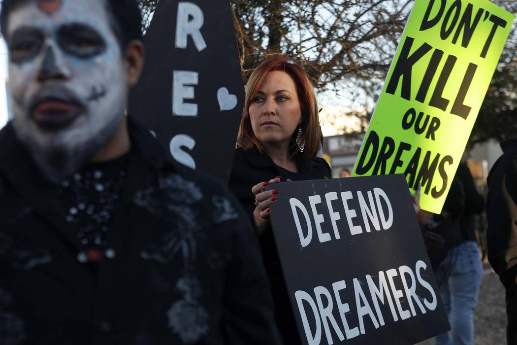 Amy Vilela, center, holds a sign to protest the Trump Administration's attempt to terminate DACA and his continual changes to the TPS program at a parking lot of the Service Employees Internationa ...