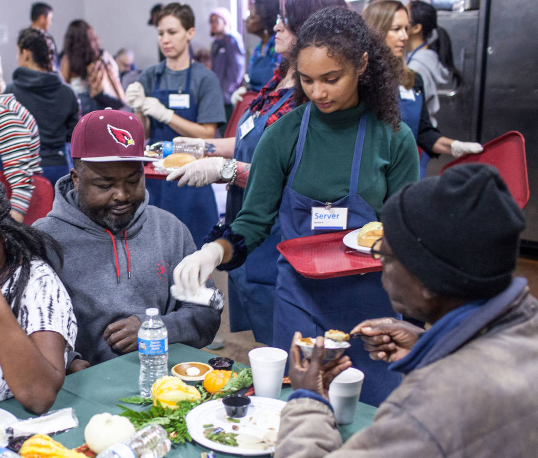 Volunteer Lehua Kanehe, 14, of Las Vegas, center, serves a free Thanksgiving meal to Lee Clark, 39, of Las Vegas, left, at Catholic Charities of Southern Nevada in Las Vegas, Thursday, Nov. 23, 20 ...