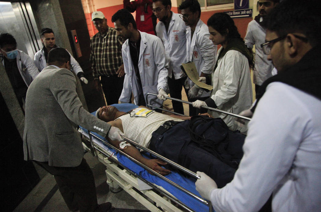 Nepalese doctors attend to an unidentified man injured in a plane crash in Kathmandu, Nepal, Monday, March 12, 2018. A plane carrying dozens of people from Bangladesh swerved erratically and flew ...