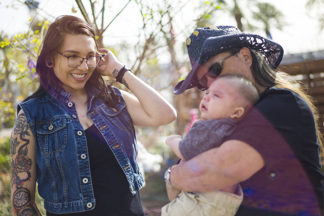 Oct. 1 shooting survivor Sue Ann Cornwell, right, holds infant Xander Finch whose mother Miriam Lujan, left, was rescued by Cornwell at the Route 91 festival, while visiting the Community Healing  ...