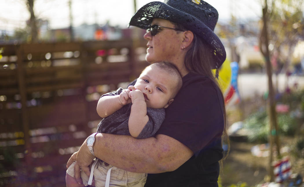 Oct. 1 shooting survivor Sue Ann Cornwell, right, holds infant Xander Finch whose mother Miriam Lujan, not pictured, was rescued by Cornwell at the Route 91 festival, while visiting the Community  ...