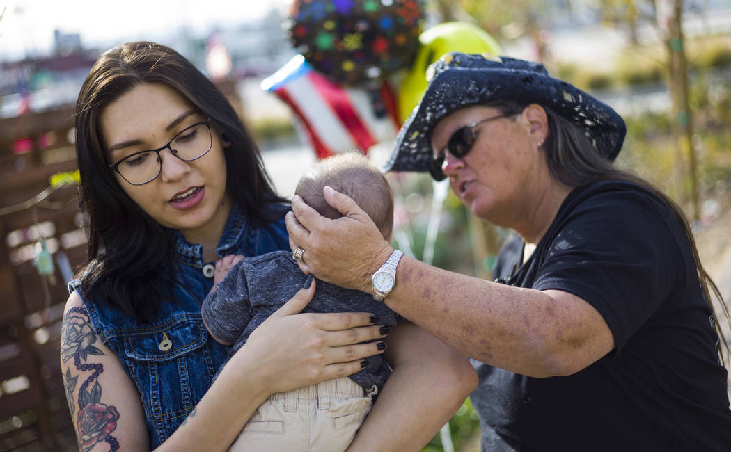 Oct. 1 shooting survivor Sue Ann Cornwell, right, talks with infant Xander Finch whose mother Miriam Lujan, left, was rescued by Cornwell at the Route 91 festival, while visiting the Community Hea ...