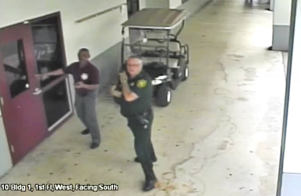 This Feb. 14, 2018 frame from security video provided by the Broward County Sheriff's Office shows deputy Scot Peterson, right, outside Marjory Stoneman Douglas High School in Parkland, Fla. The v ...