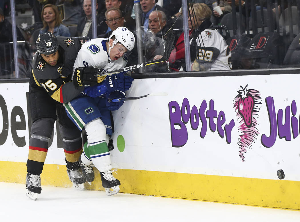 Golden Knights right wing Ryan Reaves (75) hits Vancouver Canucks defenseman Troy Stecher (51) against the glass during the first period of an NHL hockey game at T-Mobile Arena in Las Vegas on Tue ...