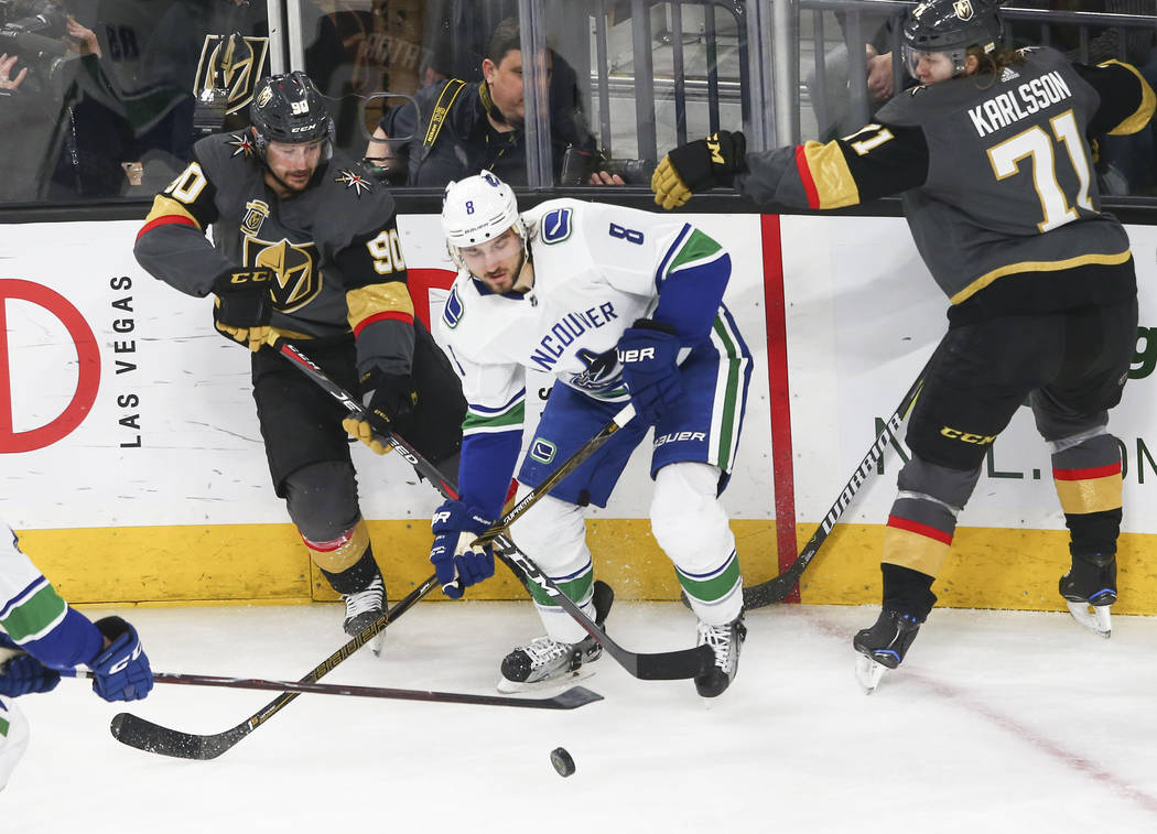 Golden Knights left wing Tomas Tatar (90) and center William Karlsson (71) go after the puck against Vancouver Canucks defenseman Christopher Tanev (8) during the second period of an NHL hockey ga ...