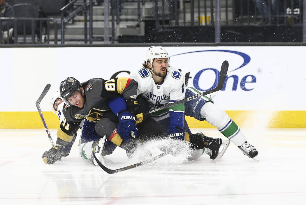 Golden Knights center Jonathan Marchessault (81) falls to the ice with Vancouver Canucks defenseman Christopher Tanev (8) and center Sam Gagner and during the first period of an NHL hockey game at ...