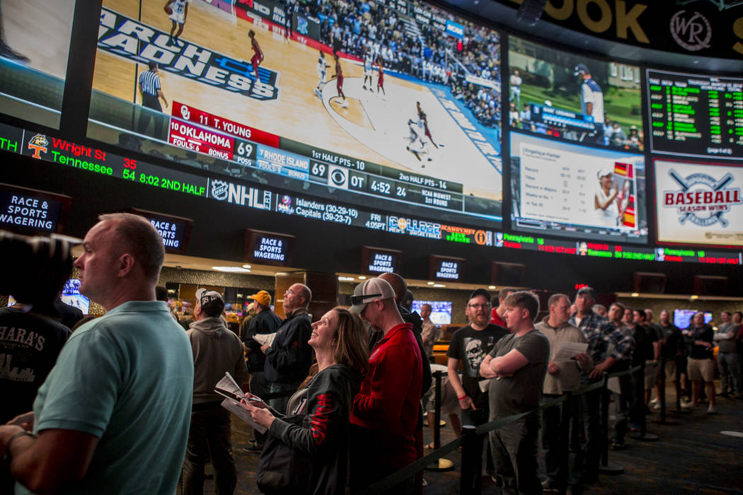 Sports betters line up to place their bets as games play overhead on giant screens at the Superbook at Westgate in Las Vegas on Thursday, March 15, 2018.  Patrick Connolly Las Vegas Review-Journal ...