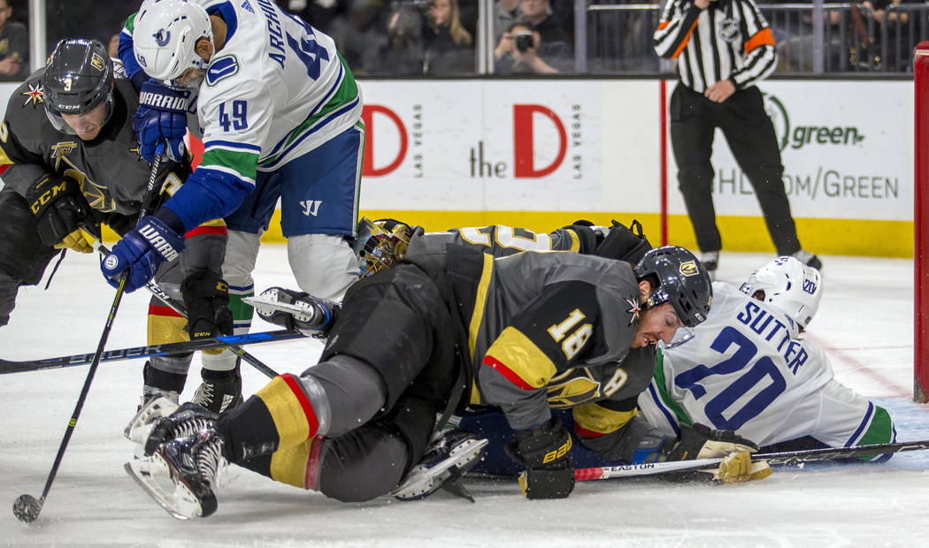 Vegas Golden Knights left wing James Neal (18) falls over Vancouver Canucks center Brandon Sutter (20) as he gets tangled up with goaltender Marc-Andre Fleury (29) after a shot attempt during the ...