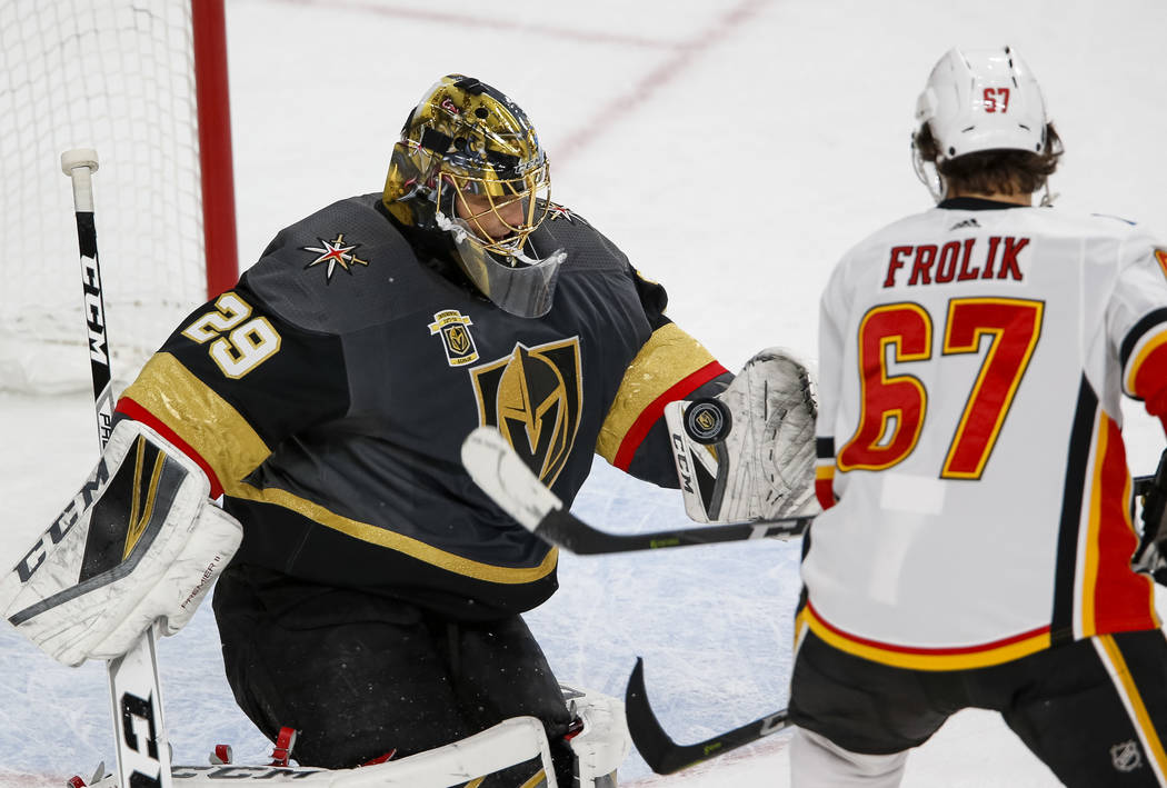 Vegas Golden Knights goaltender Marc-Andre Fleury (29) attempts to catch the puck as Calgary Flames right wing Michael Frolik (67) look for the rebound during the second period of an NHL hockey ga ...