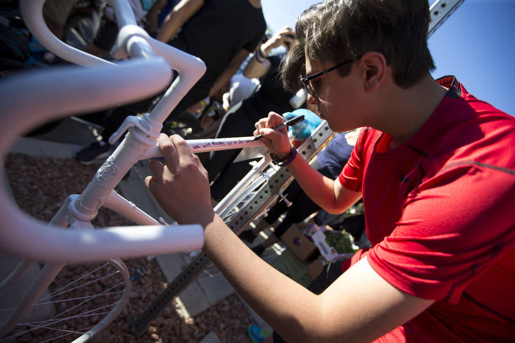 Dr. Kayvan Khiabani's son Keon Khiabani, 14, writes a message on the ghost bike of Khiabani during a memorial service at the corner South Pavillion Center Drive near West Charleston Boulevard on ...