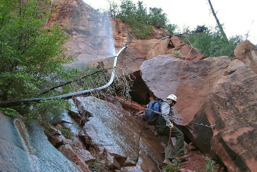 Water sprays from a break in an exposed section of the Grand Canyon transcanyon waterline as a worker attempts repairs. (National Park Service via AP, File)