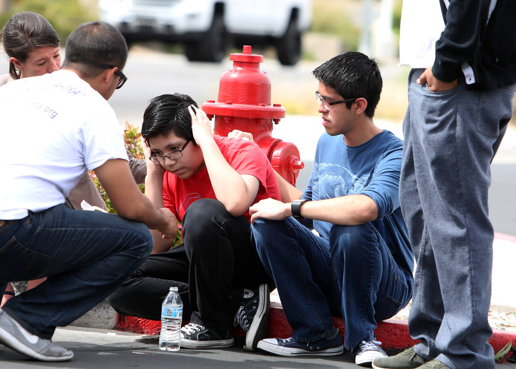 Eric Avelar, 13, center, talks with a cell phone as his brother, Ricardo Avelar, 18, second right, looks on after they held a press conference outside of U.S. Citizen and Immigration Service build ...