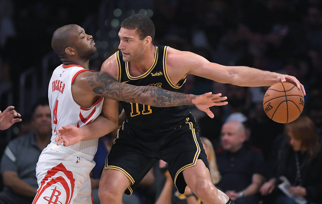 Houston Rockets forward PJ Tucker, left, reaches for the ball held by Los Angeles Lakers center Brook Lopez during the first half of an NBA basketball game Tuesday, April 10, 2018, in Los Angeles. ...