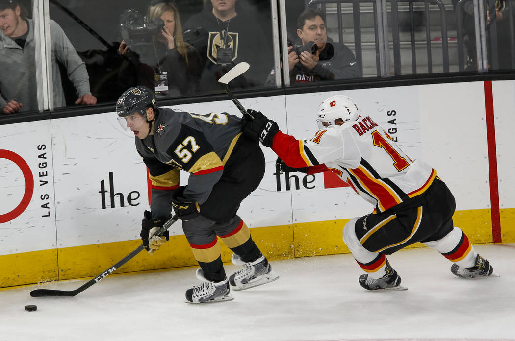 Vegas Golden Knights left wing David Perron (57) controls the puck as Calgary Flames center Mikael Backlund (11) follows behind during the second period of an NHL hockey game at the T-Mobile Arena ...