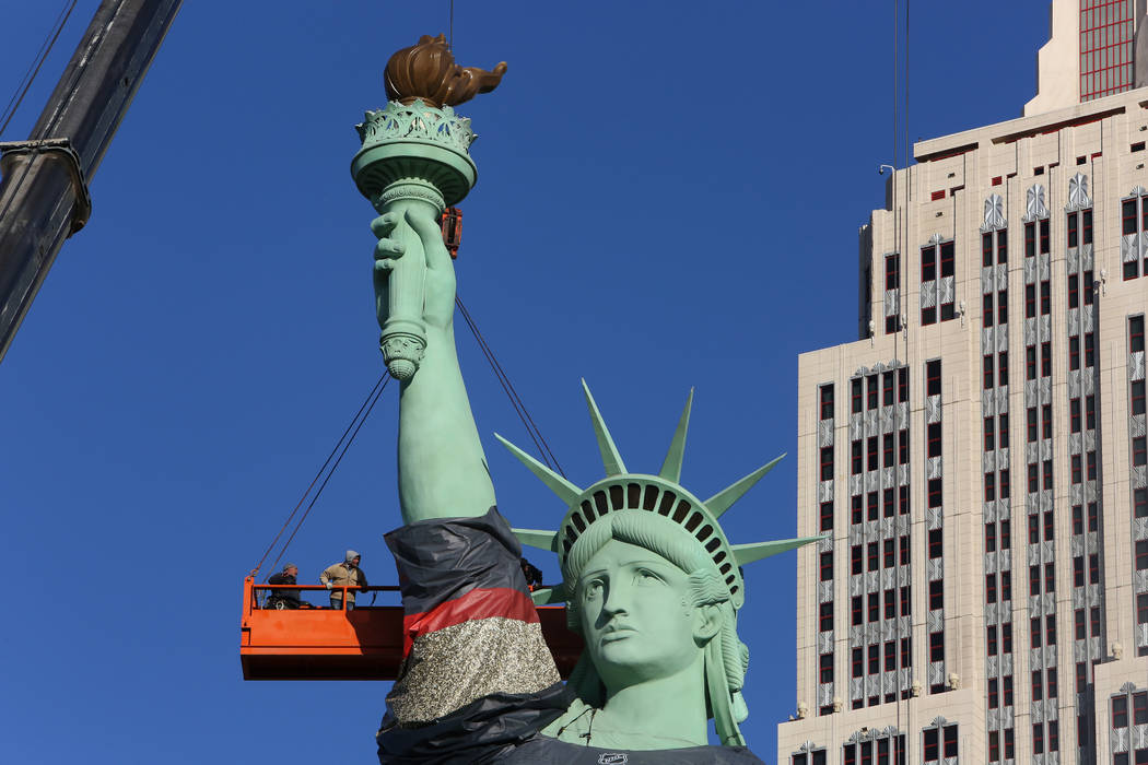 Workers install a Vegas Golden Knights jersey on the Statue of Liberty at New York-New York on Friday, April 13, 2018, on the Las Vegas Strip. (Bizuayehu Tesfaye/Las Vegas Review-Journal) @bizutesfaye
