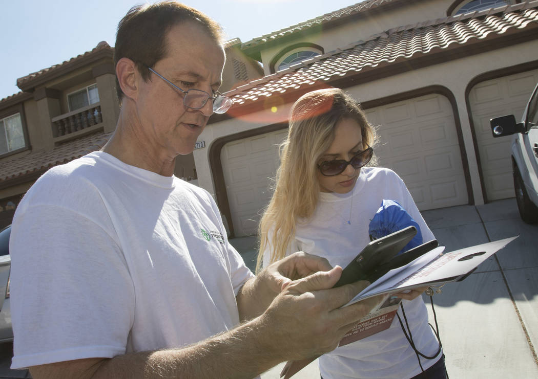 Tim Phillips, left, president of Americans for Prosperity and Field Director Erinn Mahathey check their routes on a tablet while canvassing a neighborhood for the organization in west Las Vegas on ...