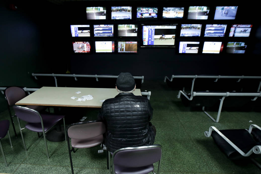 In this Nov. 30, 2017, photo, a man watches simulcast horse races at the Monmouth Park racetrack in West Long Branch, N.J. With banks of TVs tuned to all-sports stations and a spacious bar, the lo ...