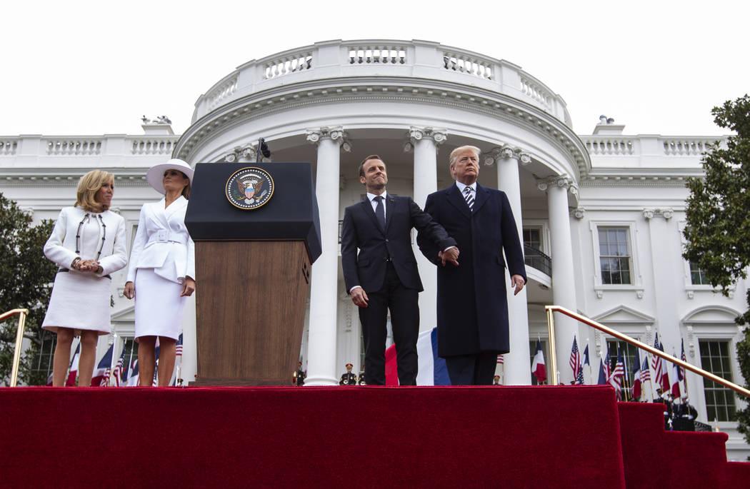 President Donald Trump and French President Emmanuel Macron, right, with first lady Melania Trump and Brigitte Macron, left, hold hands on stage during a State Arrival Ceremony on the South Lawn o ...