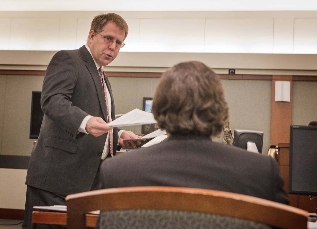Craig Mueller, representing Las Vegas City Councilman Bob Beers hands Las Vegas City Attorney Brad Jerbic a court brief during the downtown stadium petition hearing Wednesday, Feb. 4, 2015 at Regi ...