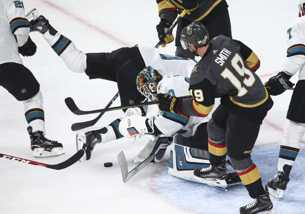 San Jose Sharks center Chris Tierney, center left, gets tripped up as San Jose Sharks goaltender Aaron Dell (30) goes for the puck while Golden Knights right wing Reilly Smith (19) looks on during ...