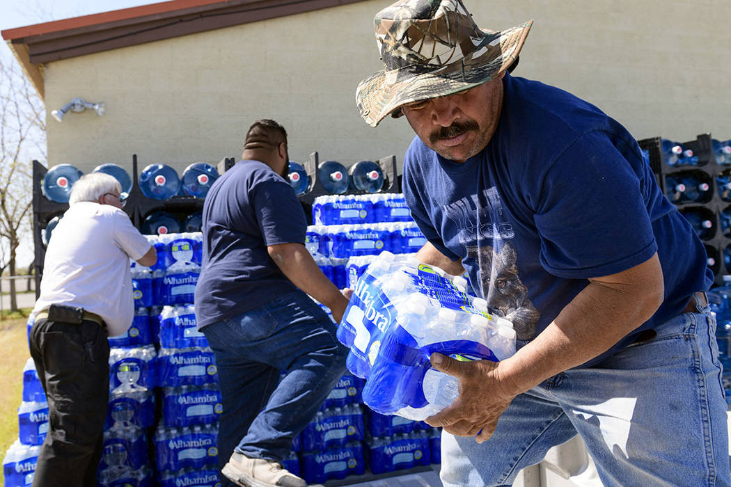 Nicolas Cuevas, right, and others load up plastic water bottles to distribute to members of the Yerington Paiute tribe after their weekly water delivery was left at the tribal border in Yerington ...