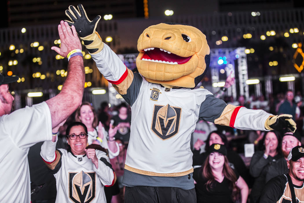 Golden Knights mascot Chance, right, celebrates with fan Bernie Lange after a second period goal at a watch party during game three of Vegas' playoff series with the San Jose Sharks on Monday, Ap ...