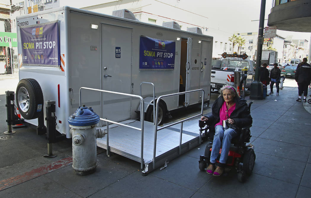In this photo taken on Thursday, April 26, 2018, a woman in a wheelchair passes a Pit Stop in San Francisco. The Pit Stop program provides public toilets, sinks, used needle receptacles and dog wa ...