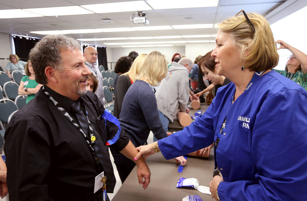 Las Vegas Academy music teacher Tony Branco learns how to apply a tourniquet with Kay Godby during University Medical Center "Stop the Bleed" training at the school Monday, April 30, 201 ...