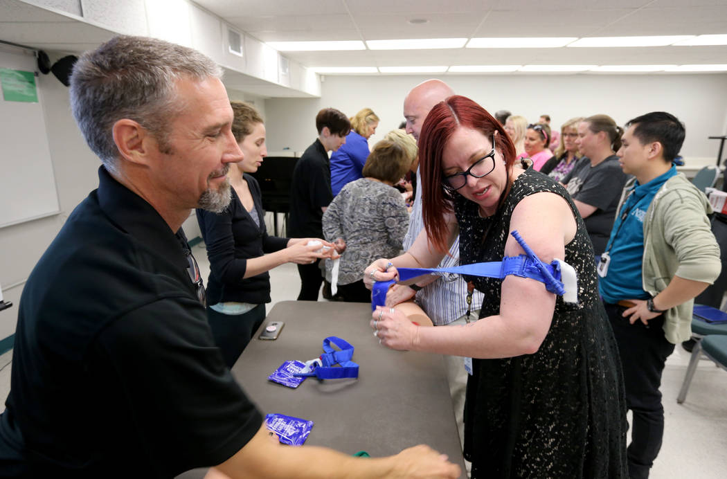 Las Vegas Academy biology and careers teacher Eva Williams learns how to apply a tourniquet with John Maholick during University Medical Center "Stop the Bleed" training at the school Mo ...