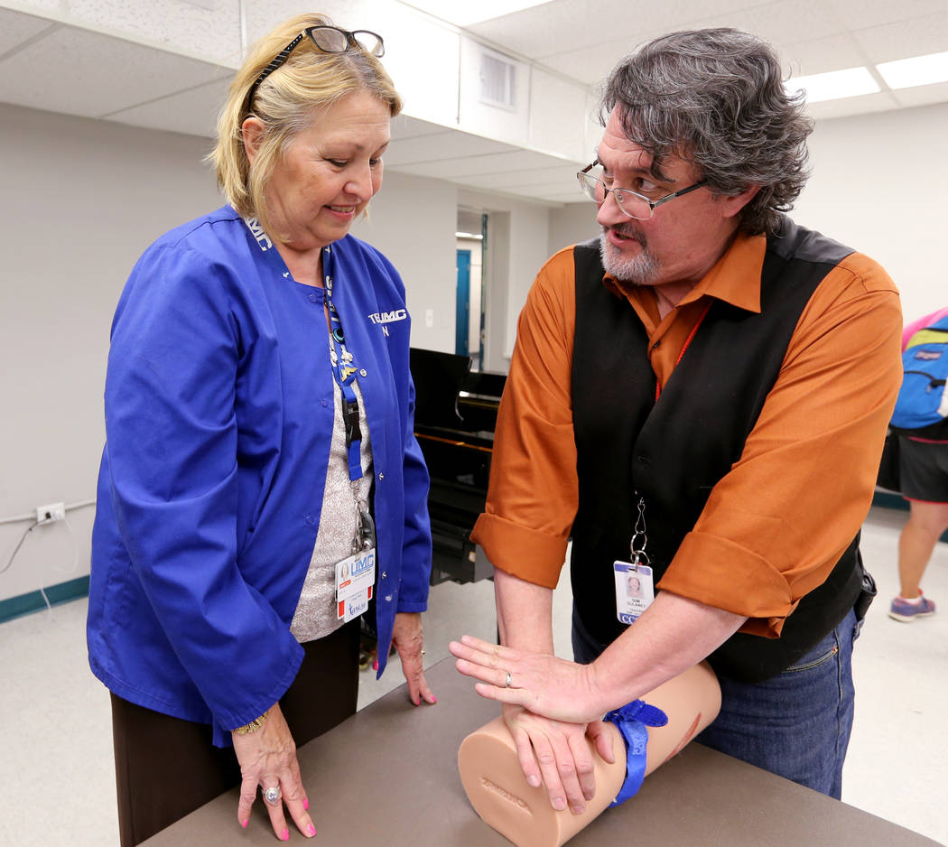 Las Vegas Academy film production and visual arts instructor Sim Dulaney, right, learns how to apply a pressure to a wound with Kay Godby during University Medical Center "Stop the Bleed&quot ...