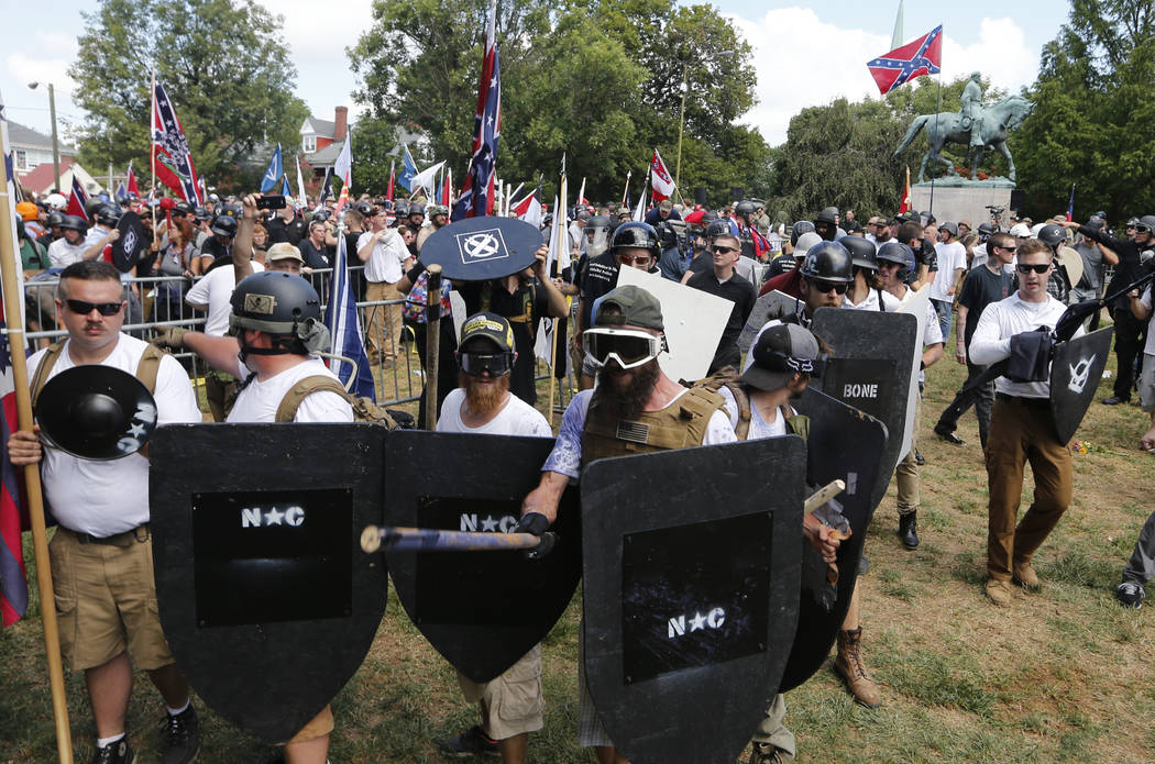 White nationalist demonstrators hold their ground as they clash with counter demonstrators in Lee Park in Charlottesville, Va., Saturday, Aug. 12, 2017. Hundreds of people chanted, threw punches, ...