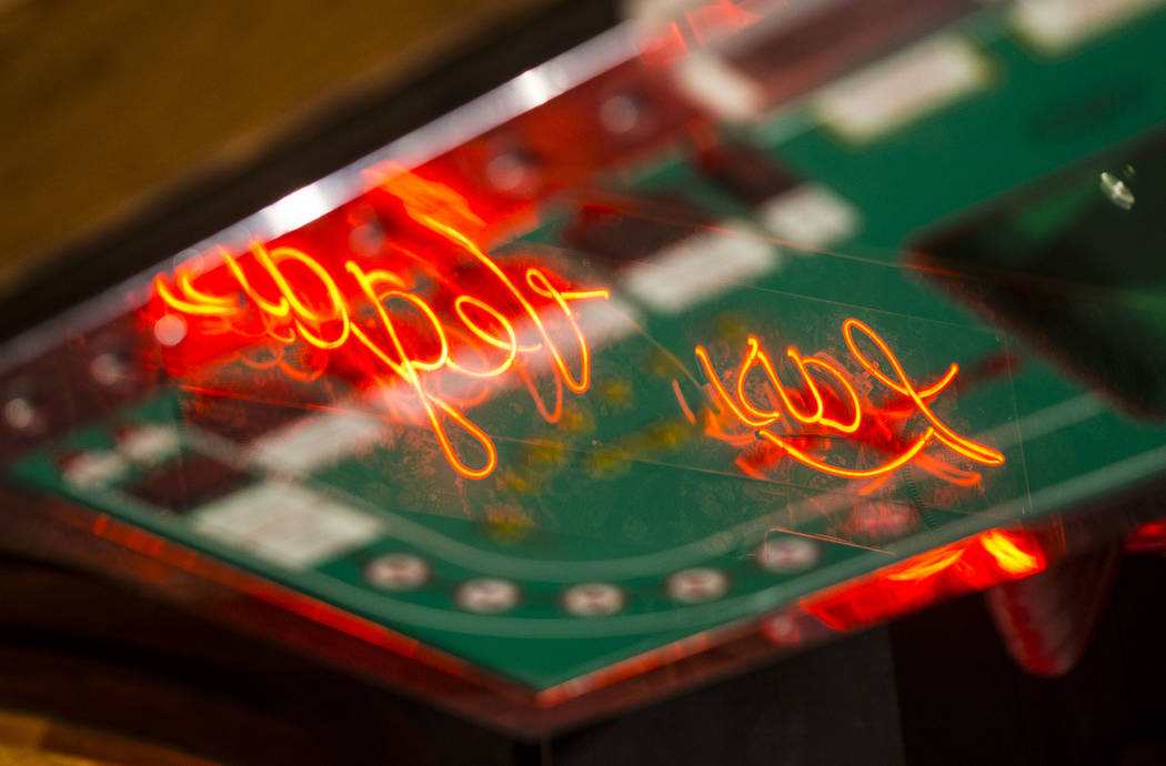 A neon Las Vegas sign is reflected in a Seven Eleven machine on display that was one of the first craps slot machines built for casino gaming at the Clark County Museum in Henderson on Wednesday, ...