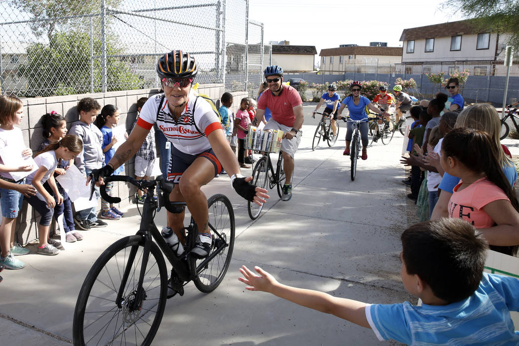 Students at Robert L. Taylor Elementary School greet bicyclists who deliver books to their school arrive during the eighth annual ÒRide for ReadingÓ event on Friday, May 11, 2018, in Hen ...