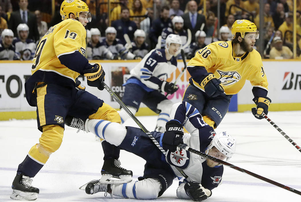 Winnipeg Jets left wing Nikolaj Ehlers (27), of Denmark, falls to the ice as he chases the puck with Nashville Predators center Calle Jarnkrok (19), of Sweden, and right wing Ryan Hartman (38) dur ...
