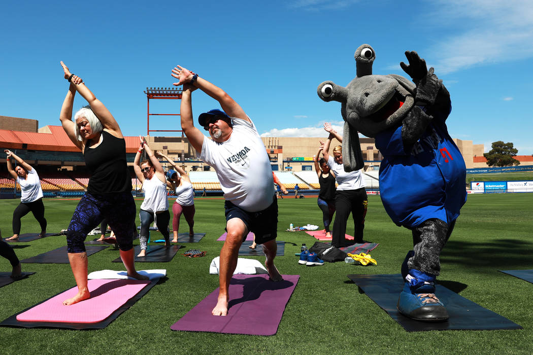 Cosmo, the Las Vegas 51s' mascot, does yoga with Chuck Johnson, general manager of the 51s, center, and his wife Andrea during a Yoga on the Field event at Cashman Field in Las Vegas on Sunday, Ma ...