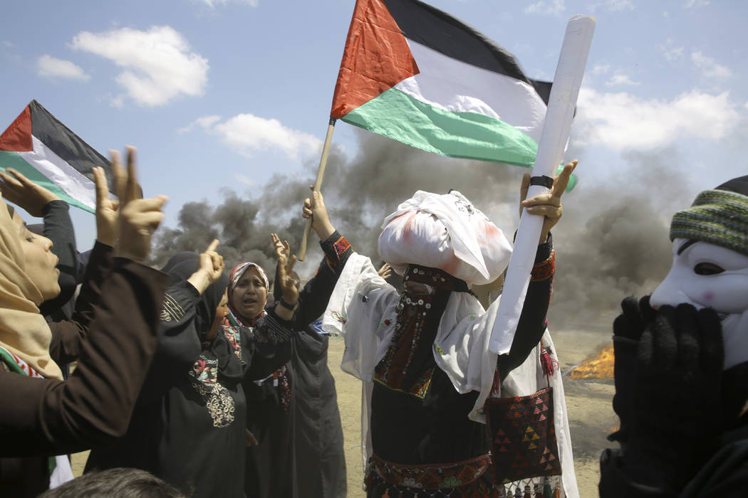 Palestinian women wave national flags and chant slogans near the Israeli border fence, east of Khan Younis, in the Gaza Strip, Monday, May 14, 2018. Thousands of Palestinians are protesting near G ...