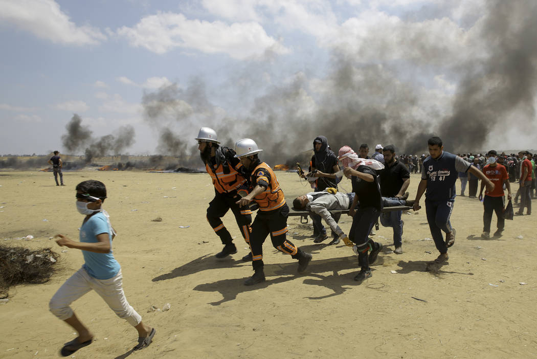 Palestinian medics and protesters evacuate a wounded youth during a protest at the Gaza Strip's border with Israel, east of Khan Younis, Gaza Strip, Monday, May 14, 2018. Thousands of Palestinians ...